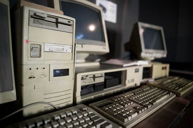 Ganz alte Computer mit alten Tastaturen in einem halbdunklen Computerraum.